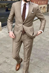 A man wears a tan two-piece suit with a white shirt, patterned tie, and brown leather loafers.