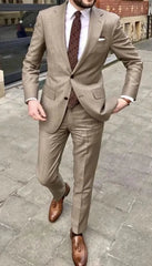 A man wears a tan two-piece suit with a patterned tie and brown tassel loafers.