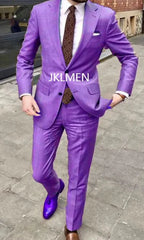A man wears a vibrant purple two-piece suit with a patterned tie and shiny purple dress shoes.