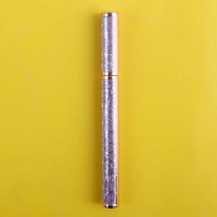 A glittery purple eyeliner pen with a rose gold cap against a yellow background.
