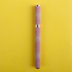 A pink glittery eyeliner pen with rose gold accents centered against a yellow background.