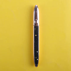 A black eyeliner pen with rose gold caps and a glittery body decorated with small gold stars.