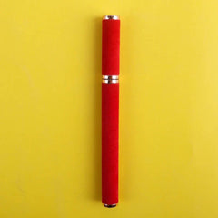 A red velvet-textured eyeliner pen with gold accents centered on a yellow background.