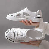A pair of white, breathable, closed-toe EVA beach sandals with a lace-up design held by hands.