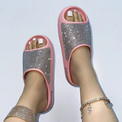 A pair of pink EVA slides featuring a sparkling rhinestone-encrusted upper strap.