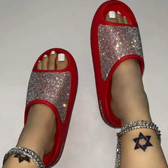 Red slide sandals with a rhinestone-encrusted upper strap and a thick flat sole.