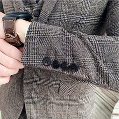 A close-up of a brown plaid blazer sleeve featuring four buttons and a matching vest.