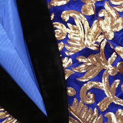 A close-up of a blue velvet blazer featuring intricate gold sequin embroidery and a black lapel.