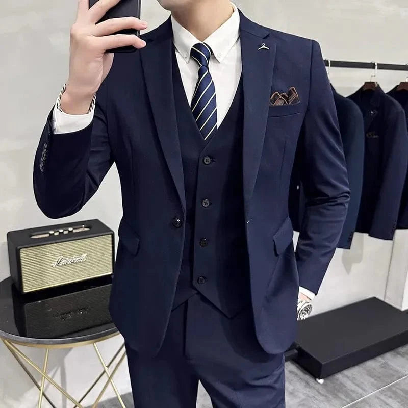 A man wearing a navy blue three-piece slim-fit suit with a white shirt and striped tie.