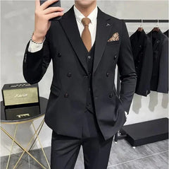 A man wears a black three-piece slim-fit suit with a white shirt and a brown tie.