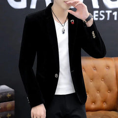 A man wears a black slim-fit single-breasted blazer with a white t-shirt and a pendant necklace.