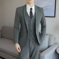 A man wears a grey three-piece suit consisting of a blazer, vest, and trousers with a black tie.