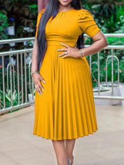 A woman wears a mustard yellow, short-sleeved, pleated midi dress with a high waist.