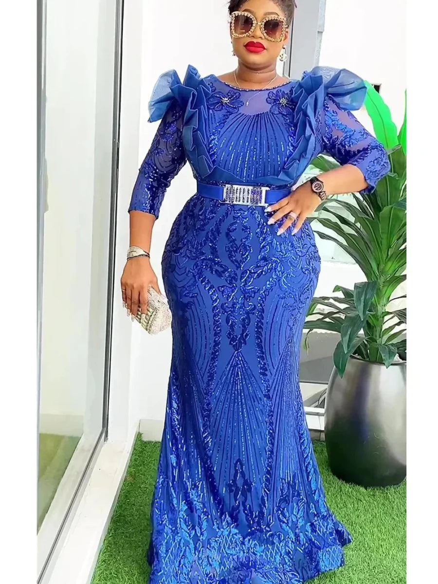 A woman wears a royal blue sequined mermaid-style evening gown with ruffled shoulders and a belt.