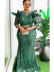 A woman wears a long, emerald green sequined mermaid gown with ruffled shoulders and a gold belt.