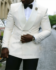 A man wears a white double-breasted slim fit blazer with a wide shawl lapel and black bowtie.