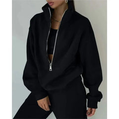 A woman wears a black long-sleeved tracksuit set featuring a loose pullover with a front zipper.