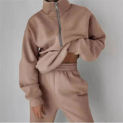 A woman wears a solid beige two-piece tracksuit featuring a quarter-zip pullover and joggers.