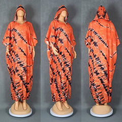 A mannequin displays a long, hooded orange kaftan dress featuring a black tie-dye pattern.