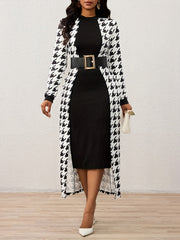 A woman wears a black knee-length dress layered under a long-sleeved houndstooth cape with a belt.