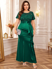 A plus-size emerald green floor-length dress with a sequined lace bodice and ruffled mermaid hem.