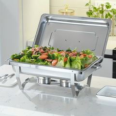 A stainless steel rectangular chafing dish filled with a salad, set on a white marble countertop.