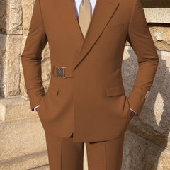 A man wears a solid brown two-piece suit featuring a metal buckle belt detail at the waist.