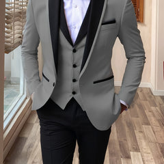 A man wears a grey three-piece suit featuring a black shawl lapel, a white shirt, and black trousers.