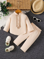 A beige long-sleeved shirt with lace embroidery and matching pants for baby boys.
