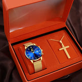 A gold-tone quartz watch with a blue dial and mesh strap paired with a cross necklace in a box.
