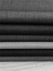 A stack of folded fabric swatches in various shades of grey and beige.