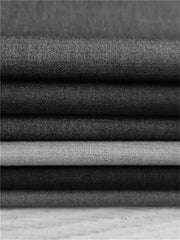 A stack of folded fabric swatches in various shades of grey for men's suits.