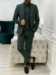 A man wears a dark green three-piece suit with a black shirt, tie, and loafers.