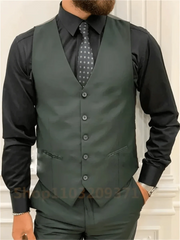 A man wears a dark green three-piece suit with a black dress shirt and a patterned tie.