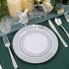 A place setting featuring white plastic plates with silver patterned rims, silverware, and a cup.