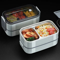 A two-layer rectangular stainless steel bento lunch box with a clear lid and divided compartments.