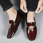 A pair of men's red slip-on loafers with a snakeskin texture and gold-tone metal embellishments.