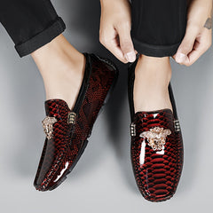 A pair of men's red slip-on loafers with a snakeskin texture and gold-tone metal embellishments.