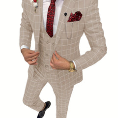 A man wears a beige plaid three-piece suit with a red patterned tie and pocket square.