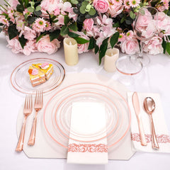 A rose gold dinnerware set with plates, cutlery, cups, and napkins arranged on a table.