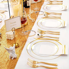 A set of clear plastic plates and gold cutlery arranged on a table with napkins and cups.
