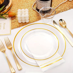 A place setting featuring clear plastic plates with gold rims, gold cutlery, and a gold-striped napkin.