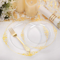 A clear plastic plate with an ornate gold rim is displayed with a matching gold plastic fork.