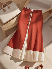 A red high-waisted midi skirt with a white front slit, button details, and a white hem.