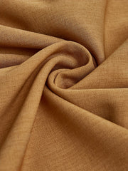 A close-up view of solid brown woven fabric with soft folds and a subtle diagonal texture.