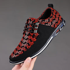 A hand holds a black and red patterned lace-up casual shoe with a white and black rubber sole.