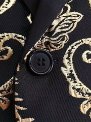 A close-up of a black men's suit jacket featuring a textured gold floral pattern and a button.