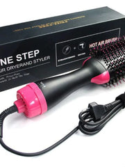 A black and pink hot air brush with a power cord sits in front of its product box.