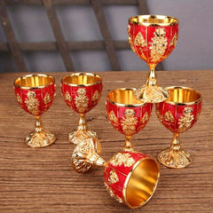 A set of six small, vintage-style metal goblets featuring red enamel and gold embossed floral detail.