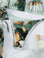 A four-piece bikini set featuring a green and gold marble print with a matching cover-up.